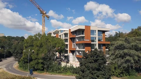 Modern Residential Building Under Construction with Yellow Tower Crane and Sky Stock Footage 346697697