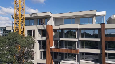 Modern Residential Building Under Construction with Yellow Tower Crane and Sky Stock Footage 346699059