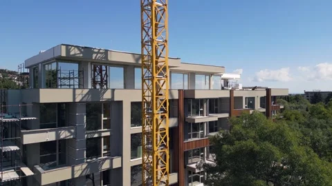 Modern Residential Building Under Construction with Yellow Tower Crane and Sky Stock Footage 346699271