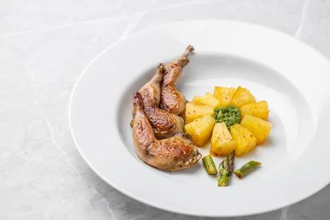 Modern restaurant dish of roasted quail legs decorated with pineapple slices. Stock Photos