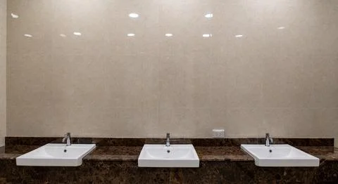 Modern restroom interior featuring multiple sinks aligned in a row represen.. 库存照片