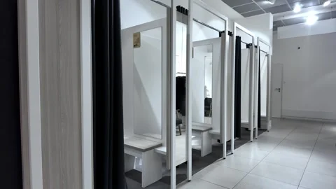 Modern retail fitting rooms featuring privacy curtains, mirrors, and seatin.. Stock Footage 318008705