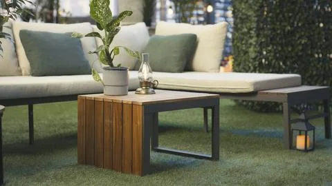 Modern rooftop seating area with plants, wooden table and lantern Stock Photos