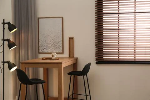 Modern room interior with table set, window blinds and stylish decor elements Foto stock