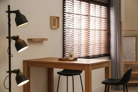 Modern room interior with table set, window blinds and stylish decor elements Foto stock