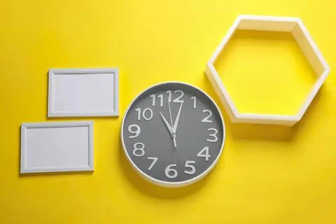 Modern round gray wall clock with white frames on yellow background Stock Photos
