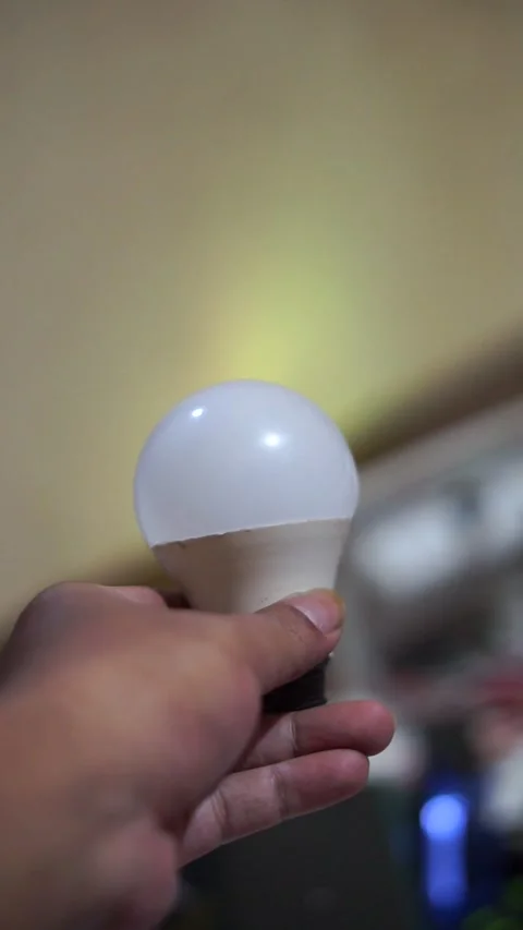 Modern round LED light bulb held in hand with soft lighting and a blurred Stock Footage 335591797