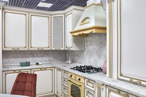 Modern rustic style kitchen with gas hob, oven and hood in white and gold col Stock Photos