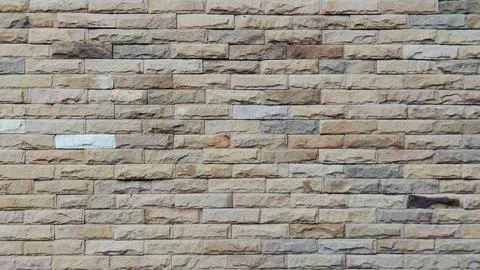 Modern sandstone brick wall background with rough texture. Stock Photos