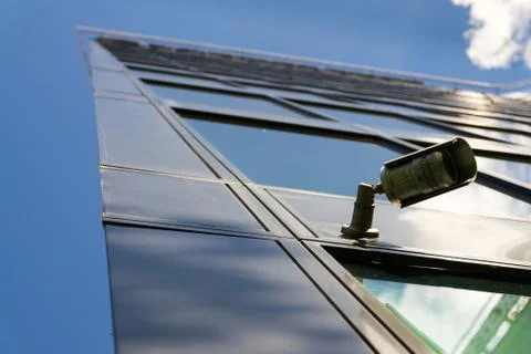 Modern security camera attached to wall with windows in background 写真素材