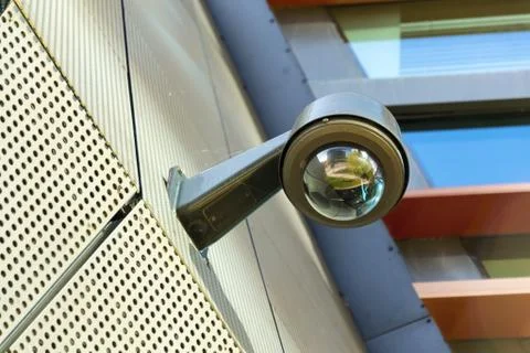 Modern security camera attached to wall with windows in background 写真素材