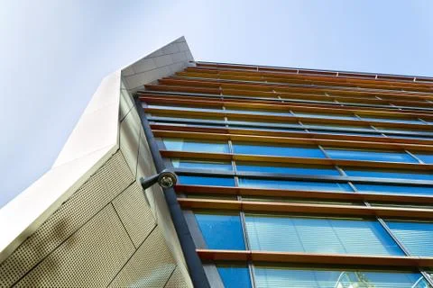 Modern security camera attached to wall with windows in background Стоковые фото