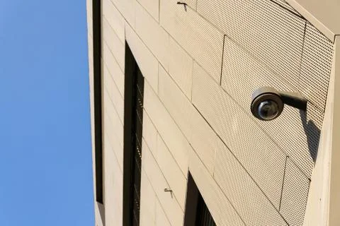 Modern security camera attached to wall with windows in background 写真素材