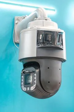 Modern security camera with bright blue backdrop, presenting sleek metallic.. Stock Photos