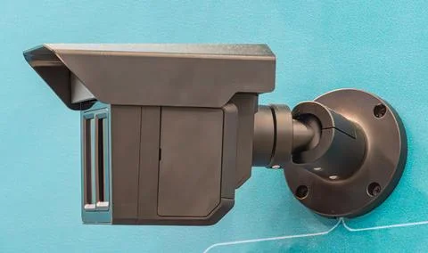 Modern security camera mounted indoors on wall bracket, sleek dark gray des.. Stock Photos