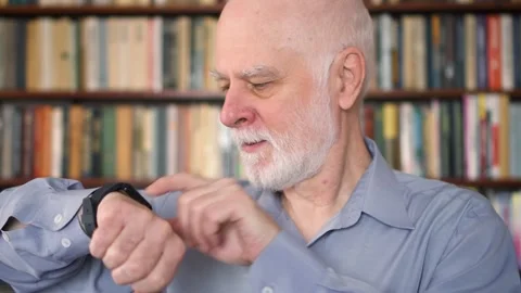 Modern senior man at home using smart watch. Retired pensioner browsing and Stock Footage 143546712