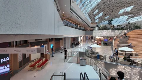 A modern shopping mall interior with a large, open space and a curved staircase. Stock Footage 287001355