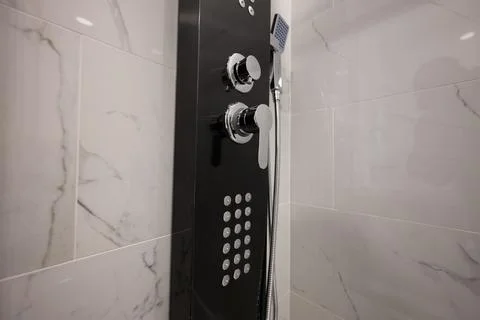 Modern shower panel with sleek chrome fixtures and controls, set against el.. Фото