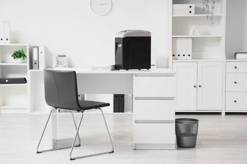 Modern shredder with documents on desk in office interior Stock Photos