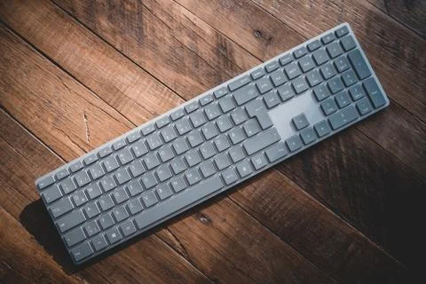 Modern silver bluetooth keyboard on an old wooden table 写真素材