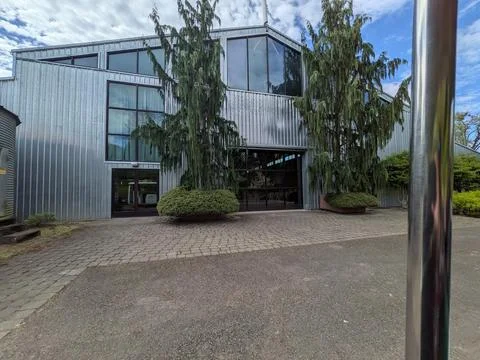 Modern silver building with expansive windows overlooking a landscaped patio Photos
