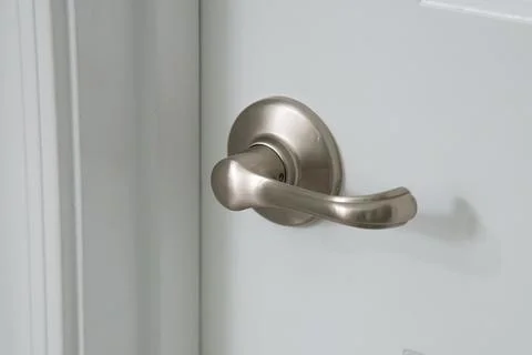 Modern silver door handle on white door Stock Photos