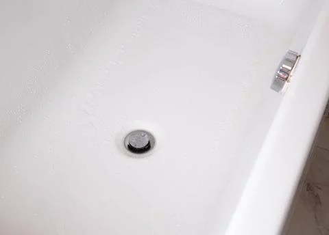 Modern silver drain plug in a new bathroom, water droplets on the walls of the Stock Photos