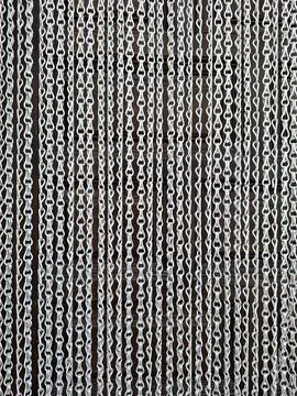 Modern silver metallic chain link fly screen curtain hanging in front of do.. Fotos Stock