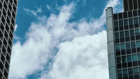A modern skyscraper against a vibrant blue sky with fluffy white clouds moving Video stock 338165299