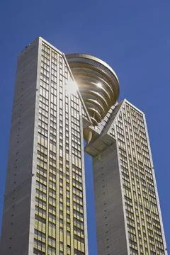 Modern skyscraper architecture with unique design against clear blue sky Stock Photos