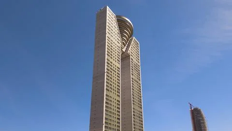 Modern skyscraper architecture with unique design against clear blue sky Stock Photos