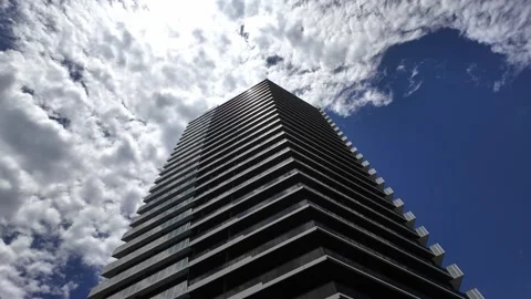 A modern skyscraper building against a dramatic cloudy blue sky. Vídeos de archivo 337277239