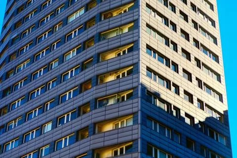 Modern skyscraper building with a grid of windows reflecting sunlight, set ag Stock Photos