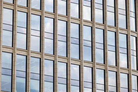 Modern skyscraper facade featuring repeating pattern of windows reflecting the Stock Photos