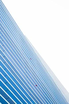 Modern skyscraper facade with parallel blue lines and white structural elements Stockfoto's