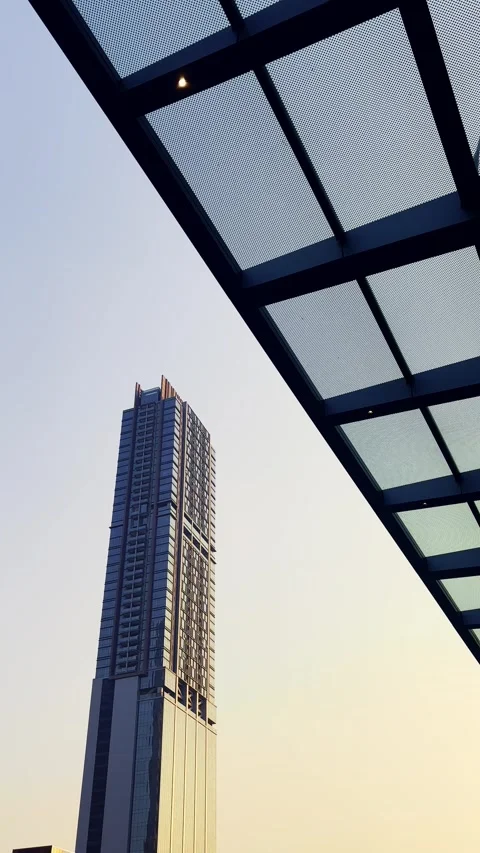 Modern skyscraper rises beside a geometric steel and glass canopy against a.. Stock Footage 340061134