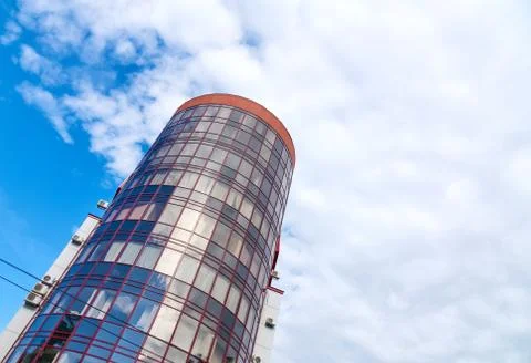 Modern skyscraper with a unique round shape, cloudy sky background, copy spac Stock Photos