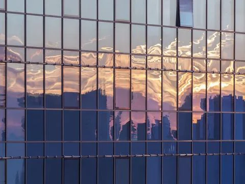 Modern skyscraper windows capturing a reflection of a sunset city. Stock Photos