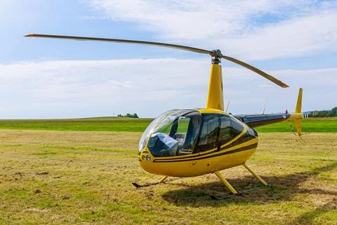 A modern small light helicopter on a grassy field against a blue sky. Front view Stock Photos