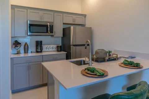 Modern small loft kitchen with refrigerator, sink, microwave with bar stools Stock Photos