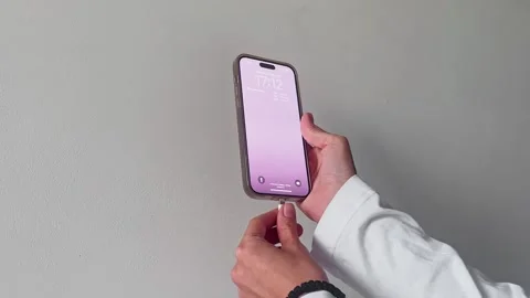 A modern smartphone is being held in a hand, set against a stylish minimalist Stock Footage 282729676