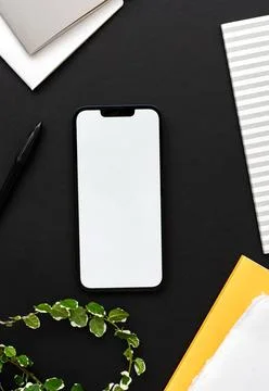 Modern smartphone on black table background with green houseplant decoratio.. Stock Photos