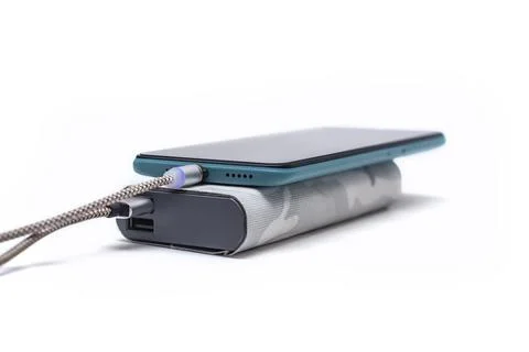 Modern smartphone is charged using a portable charger via a cable. Power ba.. Foto stock