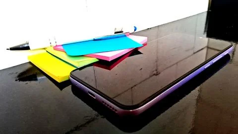 Modern smartphone on a desk. Mobile device with colorful sticky notes for Stock Photos