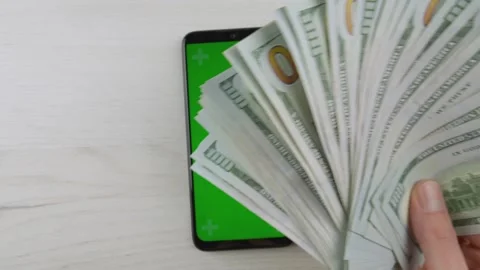 Modern smartphone with green screen lies on a white wooden table next to a fan Video stock 341032285
