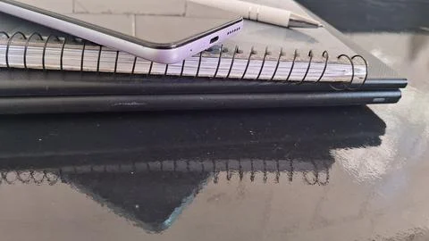 Modern smartphone resting on a spiral notebook with white pen Stock Photos