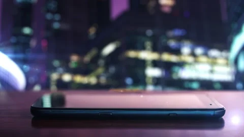 Modern smartphone resting on table with city skyline in background Stock Footage 302396678