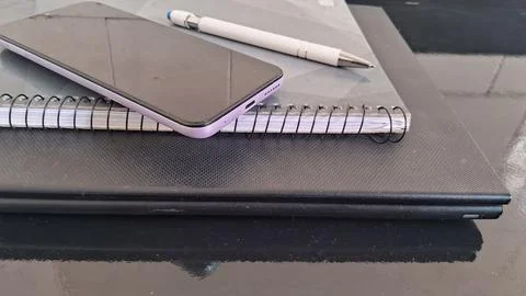 Modern smartphone rests on a spiral notebook with white pen 写真素材