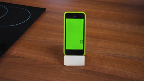 Modern smartphone in vertical position on stand, green empty screen. Mobile app Stock Footage 165784764