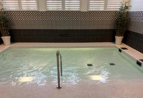 Modern spa interior featuring a tranquil thermal pool with rippling water and Stock Photos